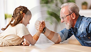 Grandfather arm wrestling with granddaughter