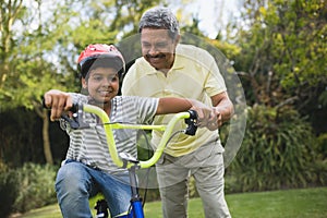 Grandfather assisting grandson while riding bicycle