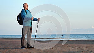 Grandfather backpacker mature man Scandinavian walking stick standing sea beach enjoy break