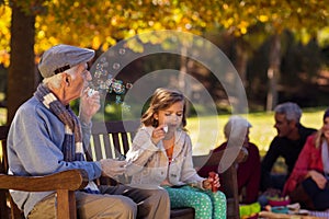 Grandfather blowing bubbles with granddaughter