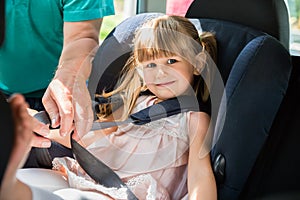 Grandfather Buckling Up On Granddaughter In Car Safety Seat photo