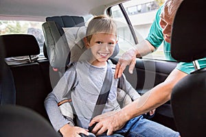 Grandfather Buckling Up On Grandson In Car Safety Seat