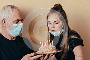 Grandfather with care gives a Caucasian girl a birthday cake and granddaughter blows out candles, enjoy the holiday during quarant