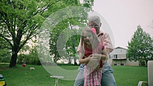 Grandfather carrying grand daughter on shoulders in nature in summer 4k