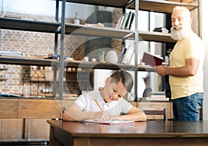 Grandfather carrying out dictation for his grandson