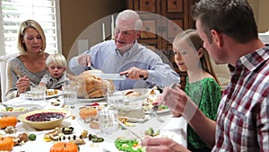 Grandfather Carving Turkey At Family Thanksgiving Meal