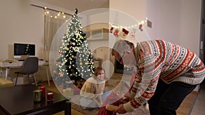 Grandfather is dancing with his grandson near the Christmas tree. Happy family celebrating christmas near the fireplace