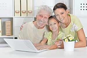 Grandfather, daughter and granddaughter using laptop