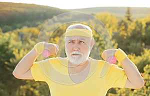 Grandfather exercising with dumbbell. Sport for senior man. Senior man in park working out with weights.