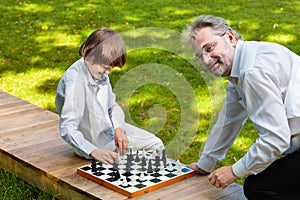 Grandfather, father and kids playing chess