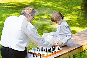 Grandfather, father and kids playing chess