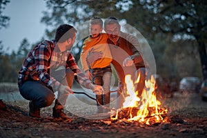 Grandfather, father and son camping together; Spring or autumn camping with campfire at night ; camping, travel, tourism, hike and