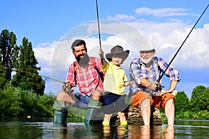 Grandfather, father and son are fly fishing on river.