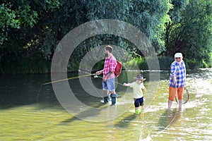 Grandfather, father and son are fly fishing on river. 3 men fishing on river in summer time. Happy grandfather and