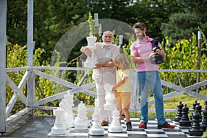 Grandfather father and son playing chess. Men in different ages playing chess board game. Weekend family. Generation men