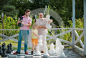 Grandfather father and son playing chess. Men in different ages playing chess board game. Weekend family. Generation men