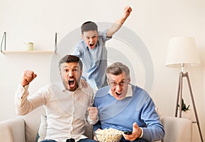 Grandfather, Father And Son Watching Football Match On TV Indoor