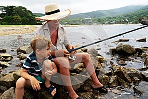 Grandfather fisher in straw hat and little male grandkid enjoying leisure activity use fishing rod