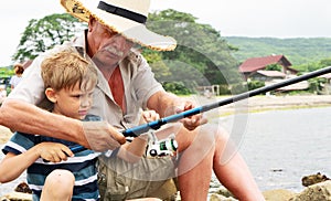 Grandfather fisher in straw hat and little male grandkid enjoying leisure activity use fishing rod