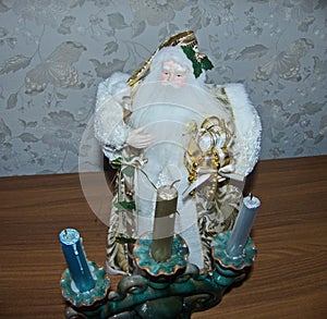 Grandfather Frost Santa Claus, St. Nicholas, Joulupukki with gifts near a candlestick with candles. The symbol of the New year