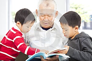 Grandfather and grandchildren reading a book