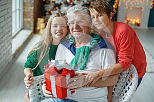 Grandfather and grandchildren in a room decorated for Christmas against the background of a Christmas tree.