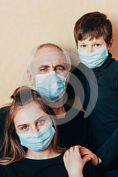 Grandfather with grandchildren on yellow background in face masks hugging and support each other in difficult times during isolati