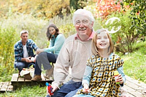 Grandfather And Granddaughter Blowing Bubbles