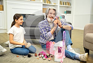 Grandfather and granddaughter enjoy playing with dollhouse