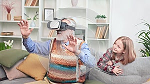Grandfather and granddaughter playing game using VR headset