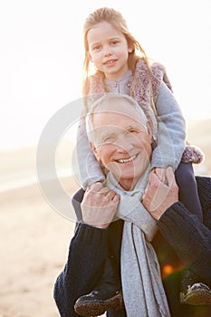Grandfather And Granddaughter Walking On Winter Beach