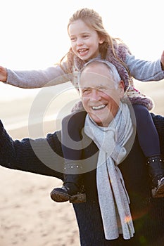 Grandfather And Granddaughter Walking On Winter Beach