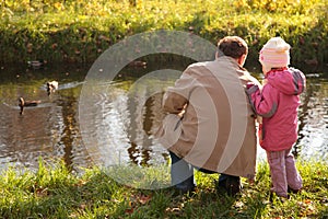 Grandfather with granddaughter in wood in autumn l