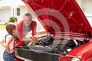 Grandfather And Granddaughter Work On Restored Classic Car