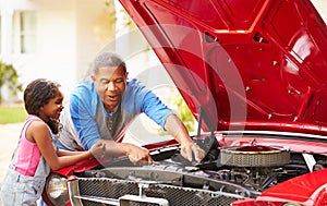 Grandfather And Granddaughter Working On Restored Car