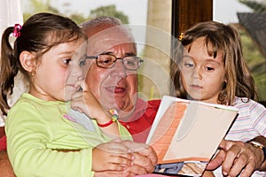 Grandfather and granddaughters reading together