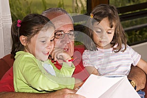 Grandfather and granddaughters reading together