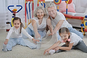 Grandfather and grandmother together with their granddaughters are training