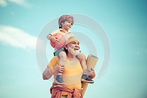 Grandfather and grandson with basketball ball and yoga mat in hands. Senior man and cute little boy exercising on blue