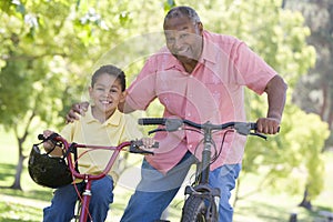 Grandfather and grandson on bikes outdoors smiling photo