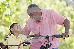 Grandfather and grandson on bikes outdoors smiling