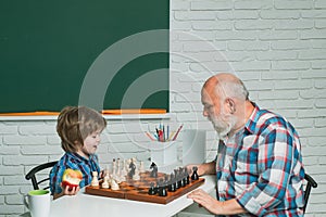 Grandfather and grandson boy playing chess, men generation. Different ages, grandfather and child grandson study chess
