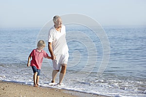 Grandfather And Grandson Enjoying Walk Along Beach