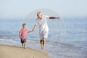 Grandfather And Grandson Enjoying Walk Along Beach