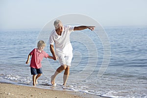 Grandfather And Grandson Enjoying Walk Along Beach