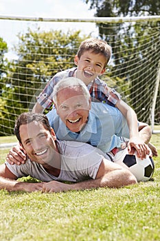 Grandfather, Grandson And Father With Football In Garden