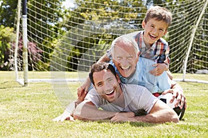 Grandfather, Grandson And Father With Football In Garden