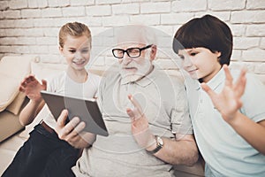 Grandfather, grandson and granddaughter at home. Grandpa and children are taking selfie.