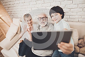 Grandfather, grandson and granddaughter at home. Grandpa and children are taking selfie.