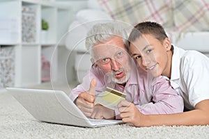 Grandfather and grandson lying on floor and using laptop, grands